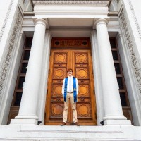 Dakota Clark standing in a grand doorway between stone columns